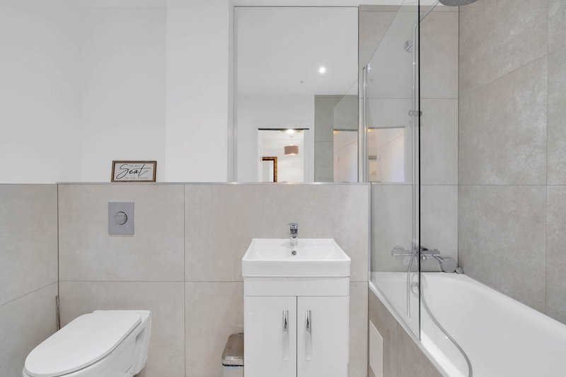 Modern bathroom with white vanity, toilet, bathtub and glass shower enclosure