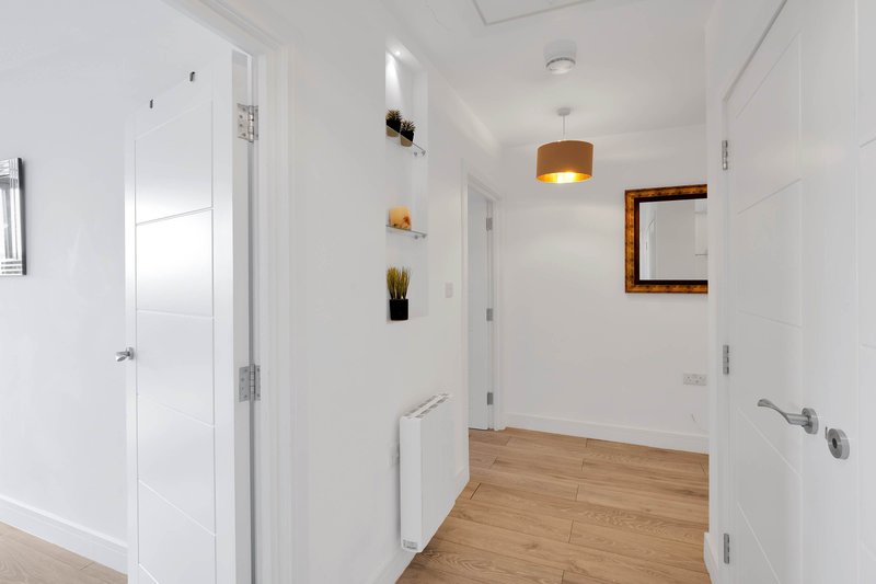 Modern hallway with white walls, wooden flooring, pendant lighting and wall shelves