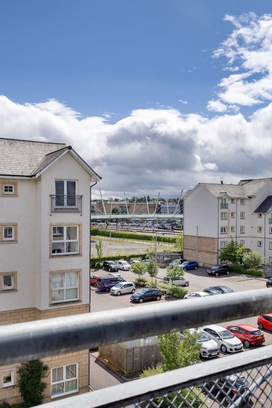 View from balcony of residential apartment building, car park, and landscaped grounds on sunny day