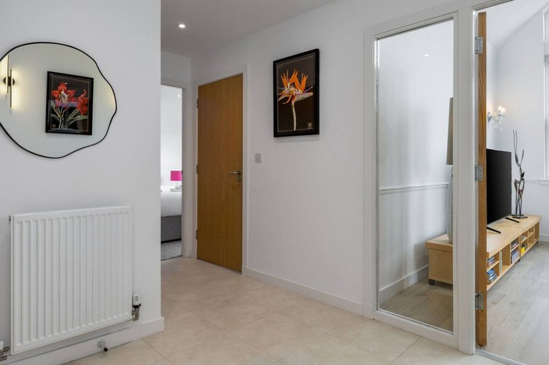 Modern hallway with white walls, wooden doors, radiator, and framed artwork on walls