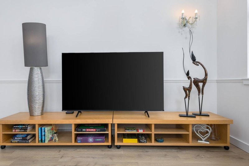 Living room with wooden TV stand, flat-screen television, decorative lamps and ornaments