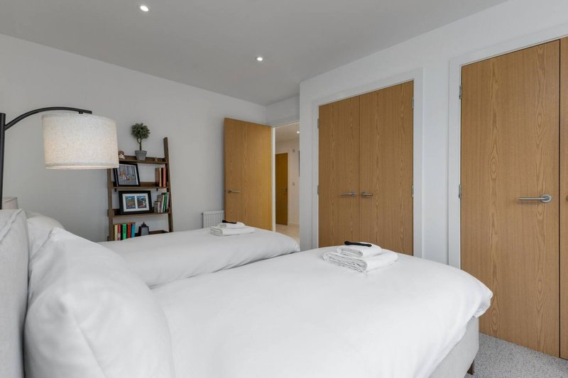 Modern bedroom with double bed, arc lamp, wooden wardrobes and shelving unit