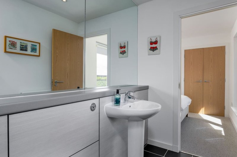 Modern bathroom with pedestal sink, vanity unit, mirror and wooden doors