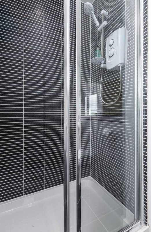 Modern bathroom shower enclosure with black linear tile walls and chrome fixtures
