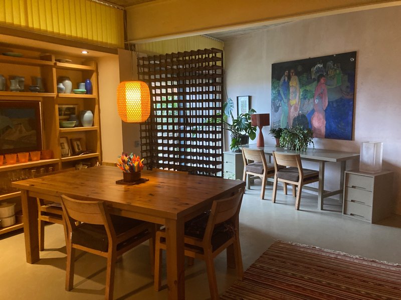 Spacious dining area with wooden table, chairs, shelving, artwork and decorative plants