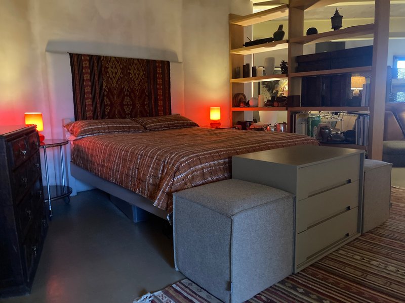Modern bedroom with single bed, red accent lighting, built-in shelving and grey upholstered bench seating