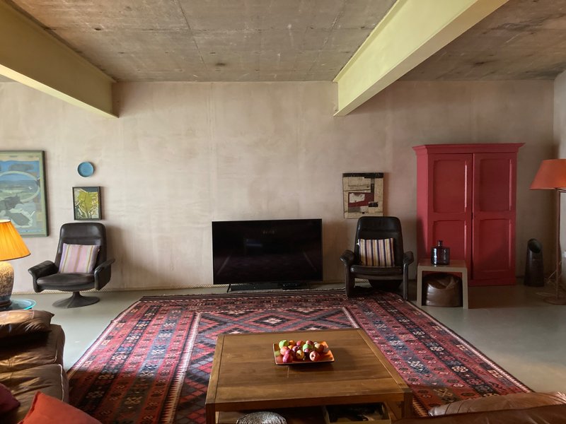 Modern living room with wooden coffee table, patterned rug, TV, red cabinet doors and seating area