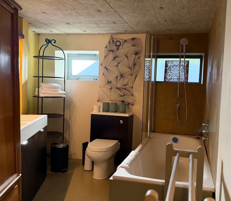 Bathroom with toilet, bathtub, shower enclosure, vanity sink and shelving
