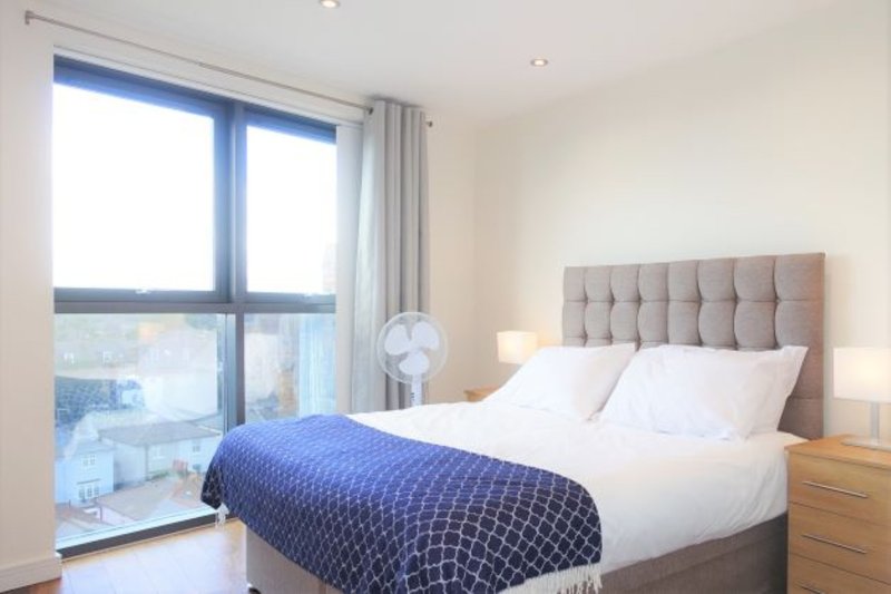 Modern bedroom with double bed, upholstered headboard, large windows and bedside lamps