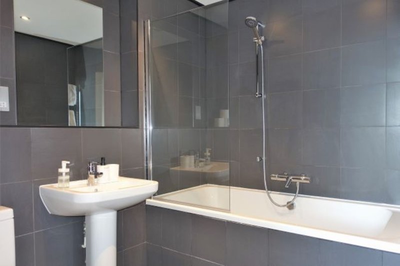 Modern bathroom with pedestal sink, large mirror, bathtub and glass shower enclosure