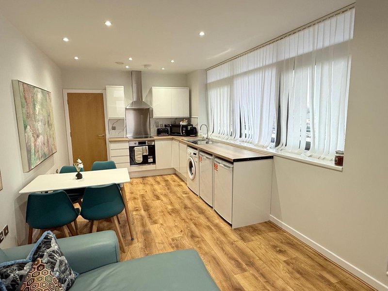 Modern kitchen-diner with white cabinetry, wooden flooring, dining table and large windows