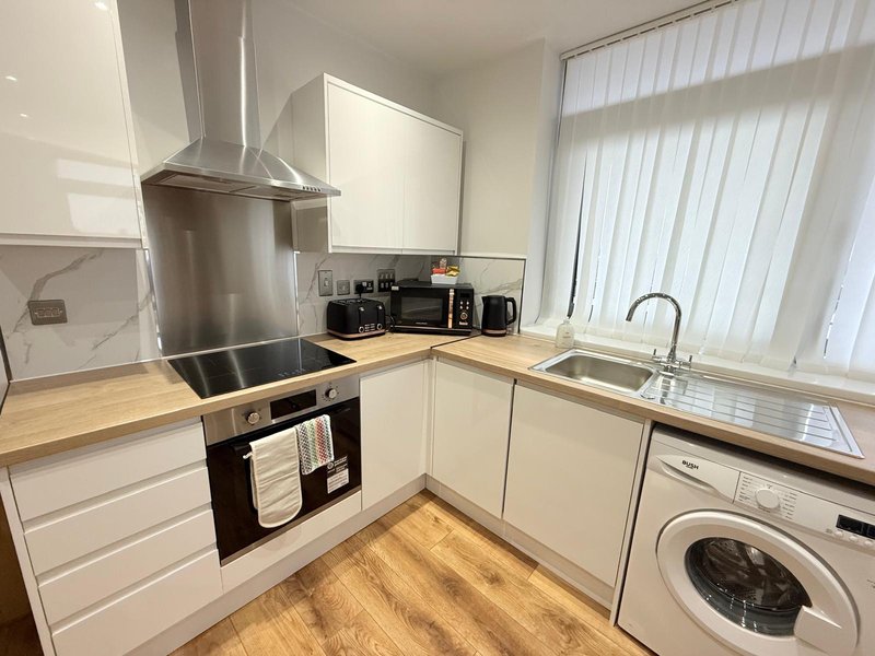 Modern kitchen with white cabinetry, stainless steel appliances, wooden countertops and flooring