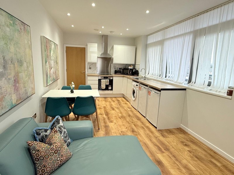 Open-plan kitchen-diner with cream cabinets, dining table, seating area and large windows