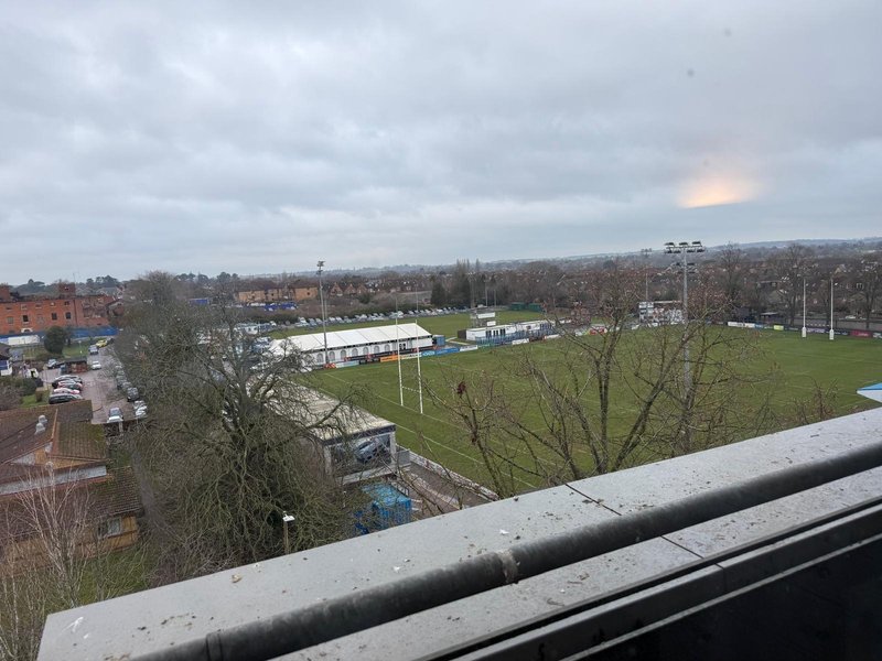 Elevated view over urban landscape with park, sports field, bare trees and cloudy sky