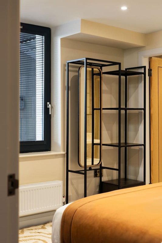 Modern bedroom with double bed, black-framed shower enclosure and window with shutters