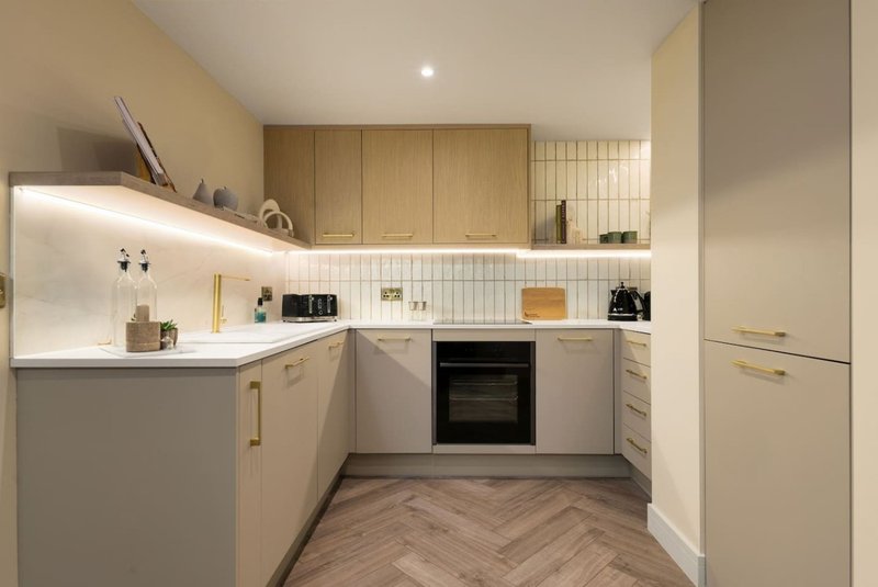 Modern kitchen with white cabinetry, wooden accents, built-in oven, and herringbone flooring