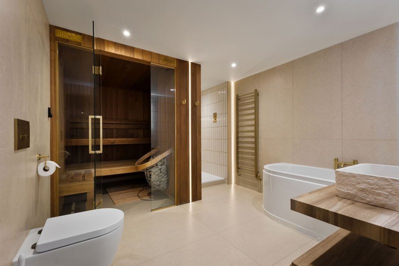Modern luxury bathroom with sauna, double vanity, freestanding tub and heated towel rail