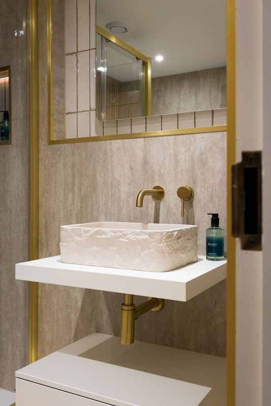 Modern bathroom with marble basin sink, brass fixtures, and gold-framed mirror