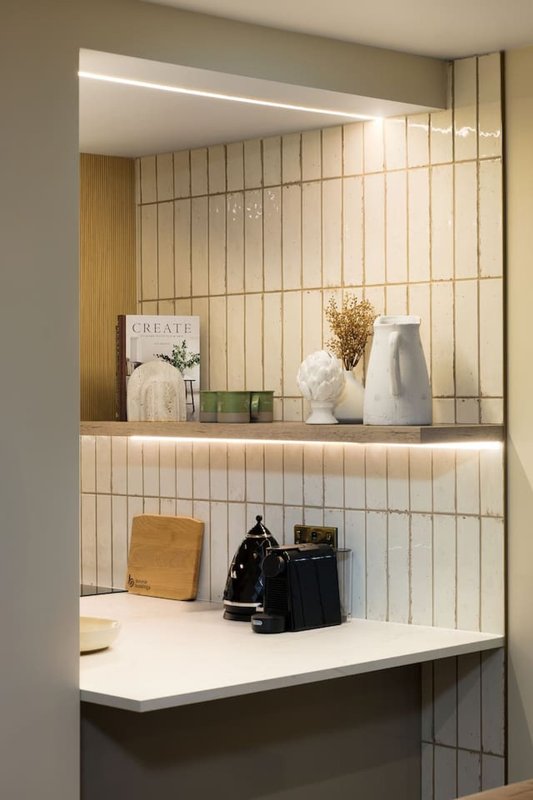 Modern built-in shelving with cream tile backsplash, decorative objects and ambient lighting