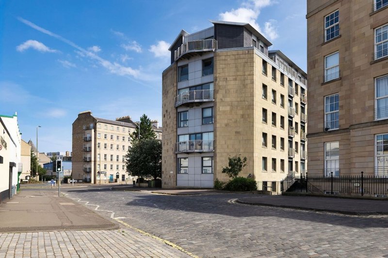 Street view of multi-storey residential buildings with stone facades and blue sky