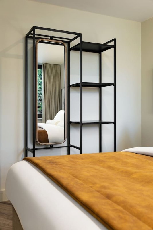 Bedroom with double bed, wooden throw, and black-framed mirror wardrobe with shelving