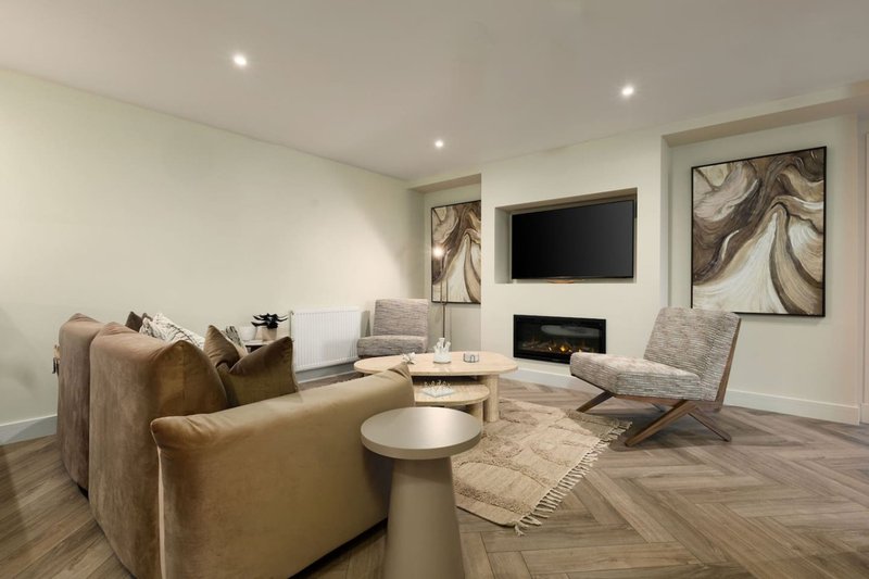 Modern living room with tan sofa, fireplace, TV, and contemporary artwork on walls