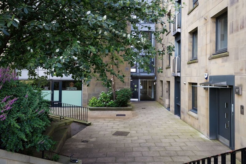 Stone courtyard with paved ground, ivy-covered walls, and residential building entrance