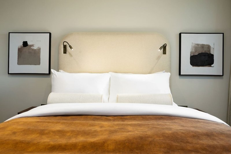 Modern bedroom with double bed, white pillows, cream headboard and framed wall art