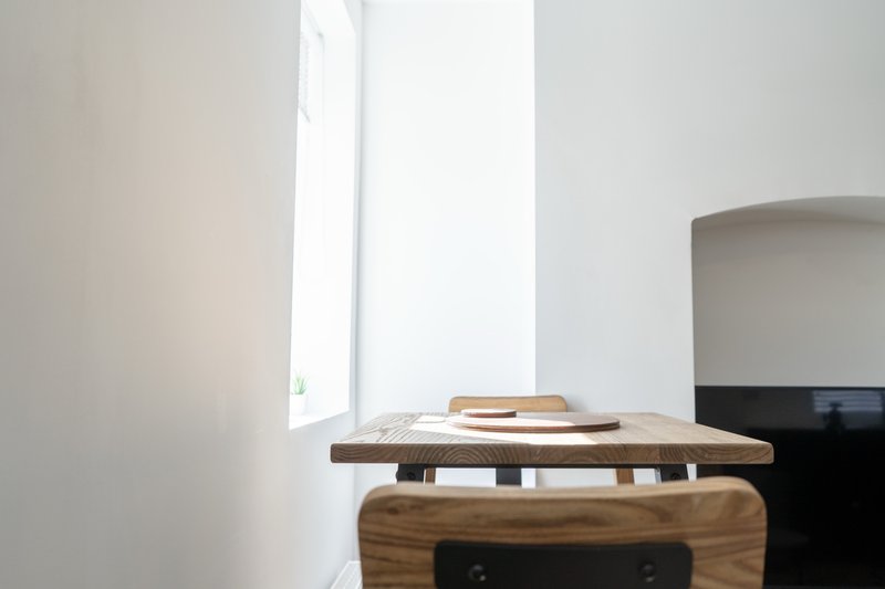 Minimalist interior with wooden desk, tall window, and modern curved furniture
