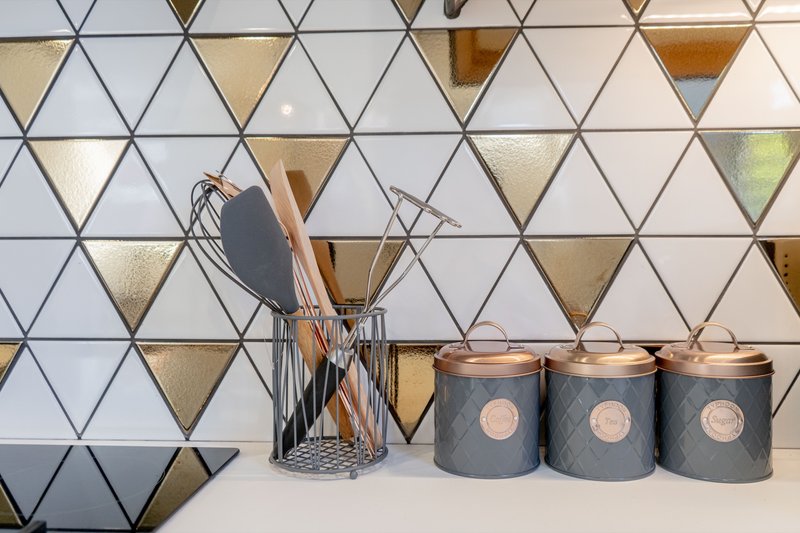 Kitchen backsplash with geometric tile pattern, utensil holder, and decorative storage canisters
