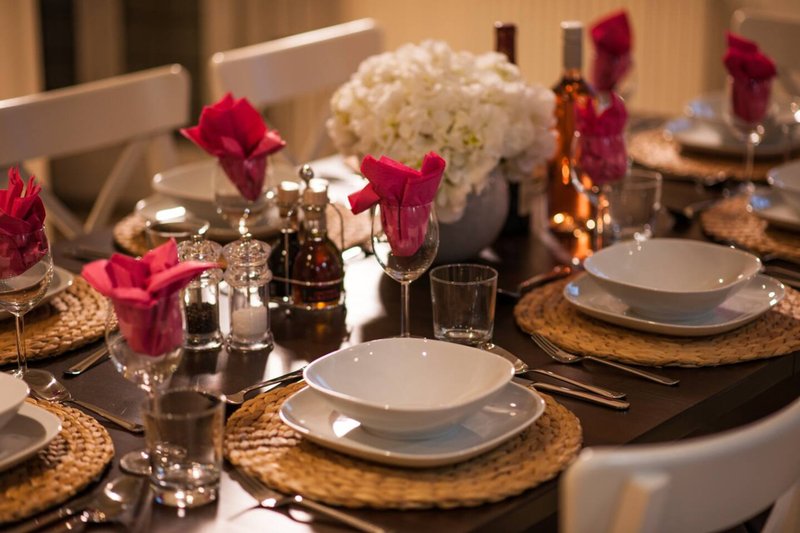 Formal dining table set with white plates, red flowers, and glassware