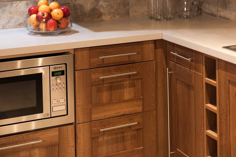Kitchen counter with wooden cabinets, stainless steel microwave, and bowl of fresh fruit