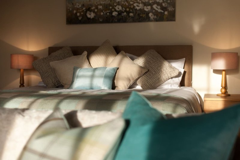 Bedroom with double bed, patterned pillows, bedside lamps, and framed floral artwork