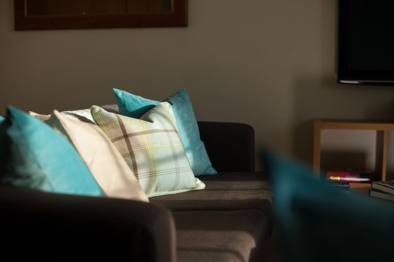Living room sofa with turquoise and cream cushions, sunlit interior space