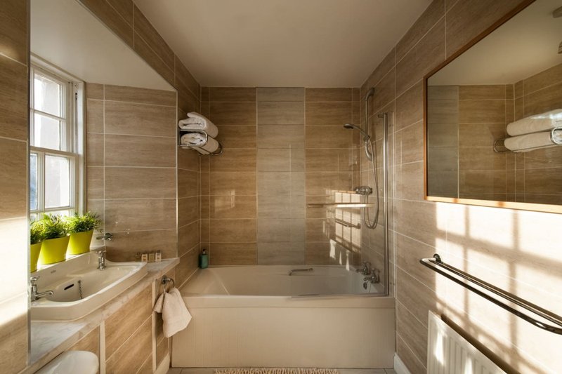 Modern bathroom with bathtub, walk-in shower, wooden tile walls, and natural light from window