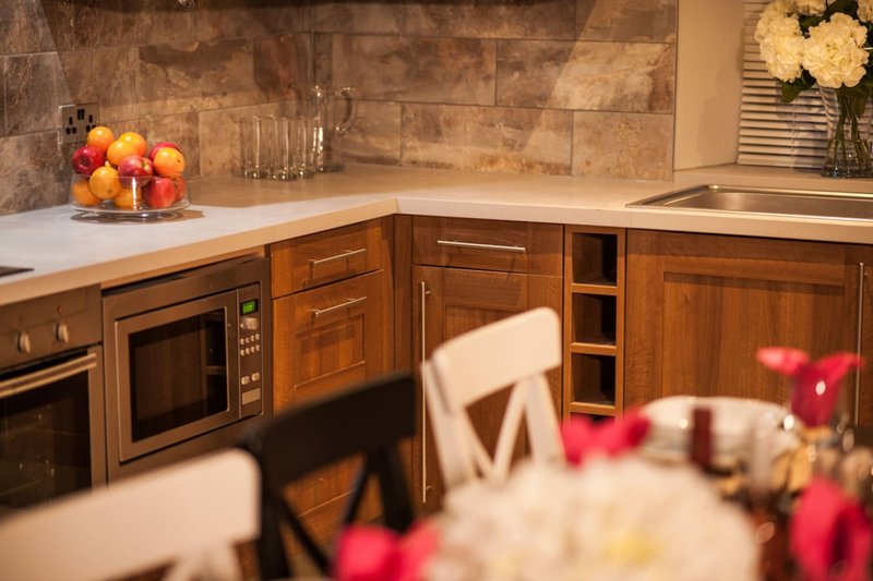 Modern kitchen with wooden cabinetry, stone backsplash, countertop fruit bowl, and flowers