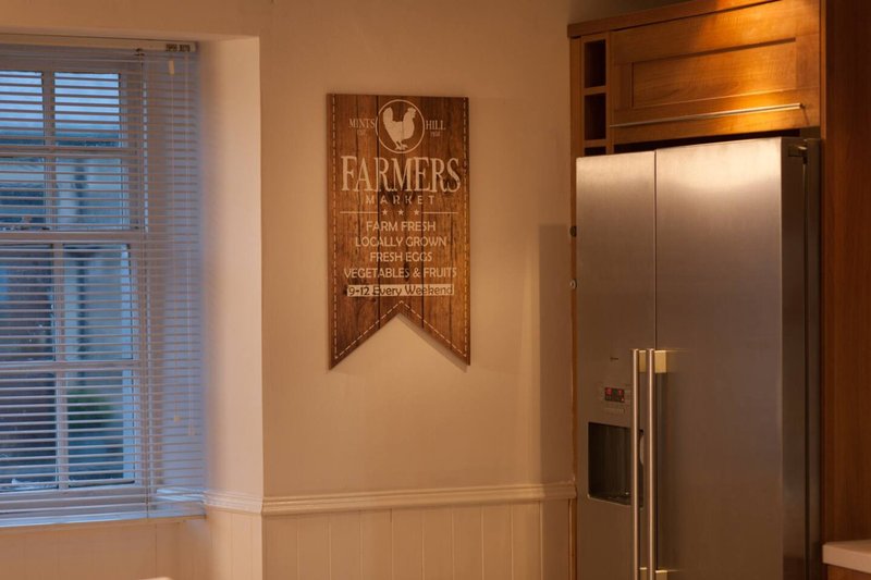 Kitchen with wooden farmers market sign, stainless steel refrigerator, and window with blinds