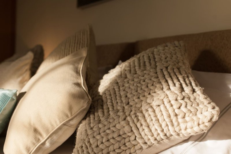 Bed with white pillows, cream knit throw blanket, and neutral bedding