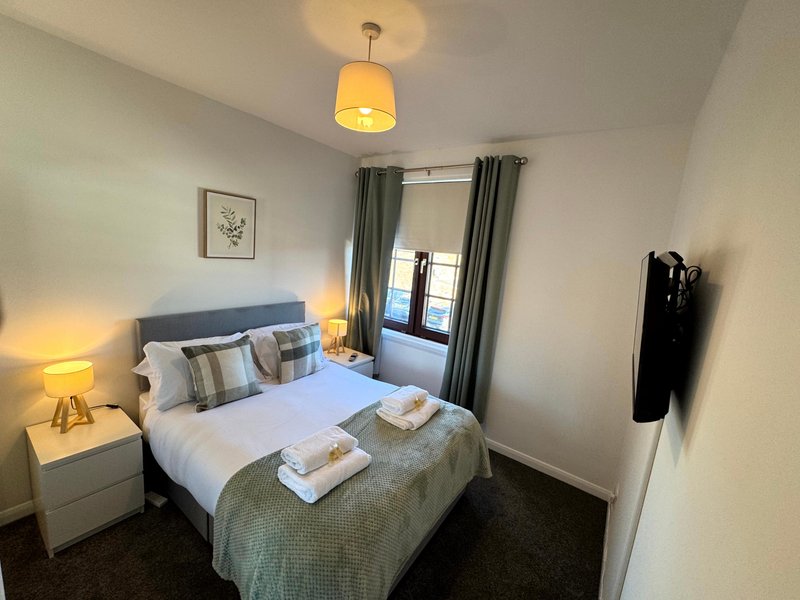 Modern bedroom with double bed, bedside lamps, grey curtains and pendant ceiling light