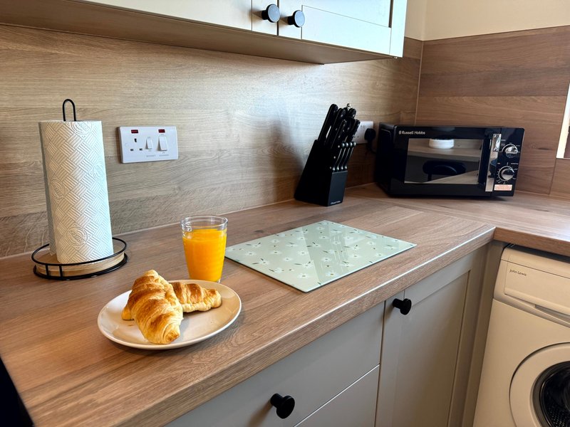 Kitchen counter with croissants, orange juice, paper towel holder and small appliances
