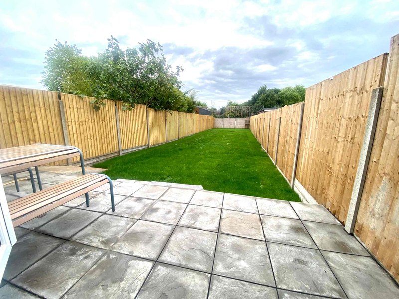 Spacious garden with patio, lawn, wooden fences and seating area