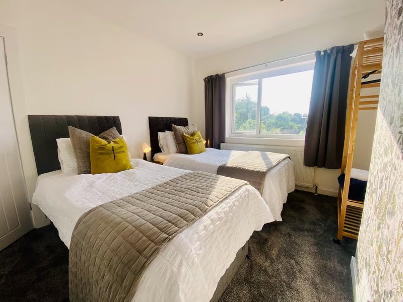 Bedroom with two single beds, yellow cushions, window with countryside view