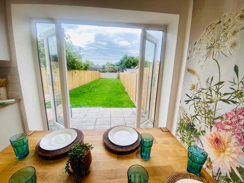Dining table with place settings overlooking garden through large glass doors