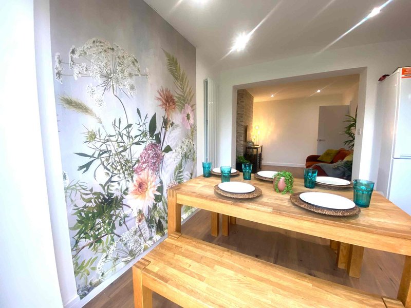 Modern dining area with wooden table, floral wall art, and place settings