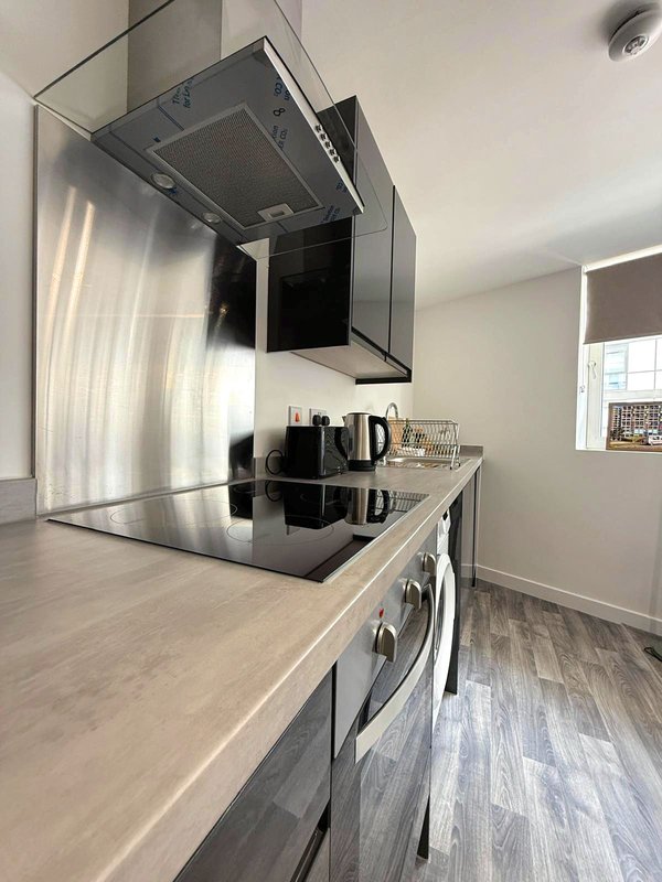 Modern kitchen with stainless steel appliances, countertop kettle, and extractor hood above cooker