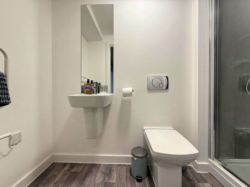 Modern bathroom with wall-mounted sink, toilet, mirror and shower enclosure