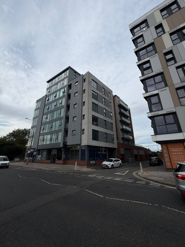 Modern multi-story apartment building exterior with street view and parked cars