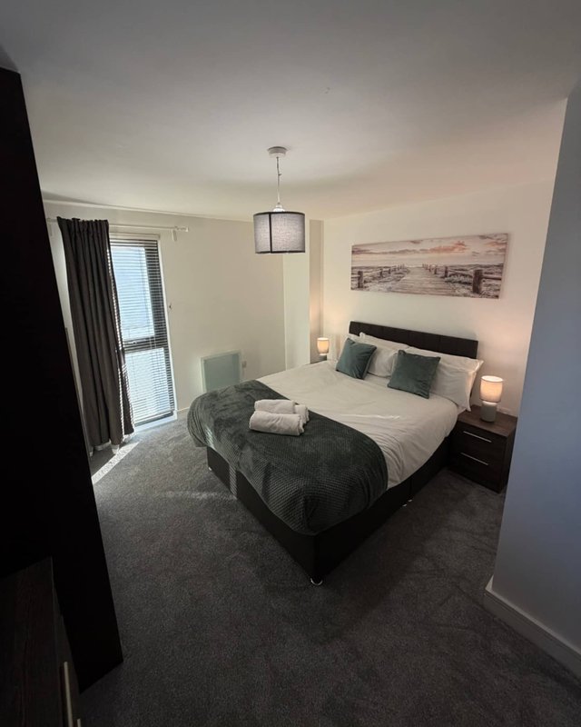 Modern bedroom with double bed, bedside lamps, wall art, and balcony access door
