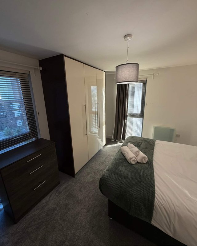 Bedroom with double bed, wardrobe, chest of drawers, pendant lamp and windows