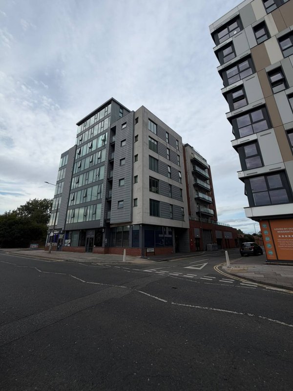 Modern residential apartment buildings on a street corner with cloudy sky
